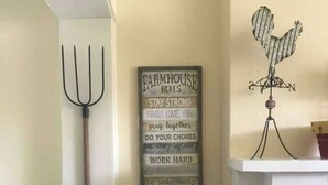 Een muur met een bord waarop boerderijregels staan en een decoratieve haan.