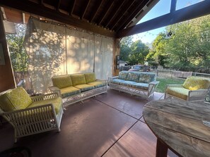 Een overdekt terras met rieten meubels en een tafel.