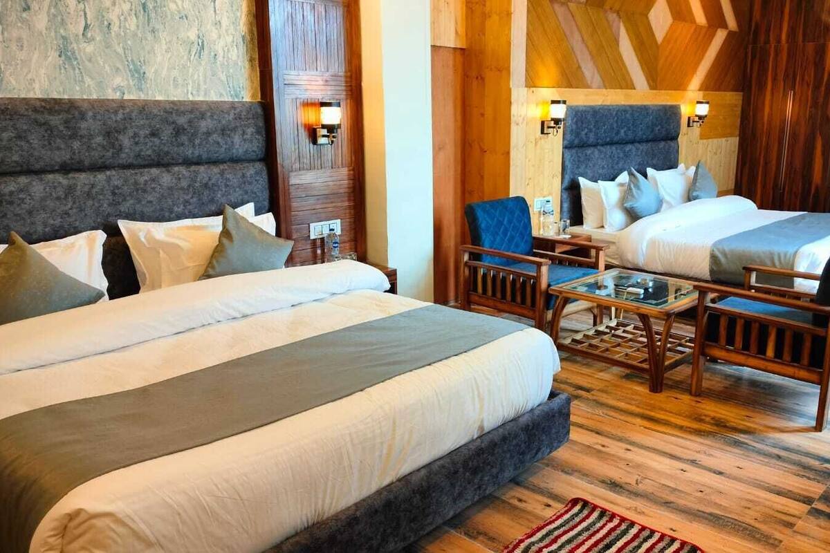 Ein Hotelzimmer mit zwei Betten, einem Sofa, einem Couchtisch und Holzboden.