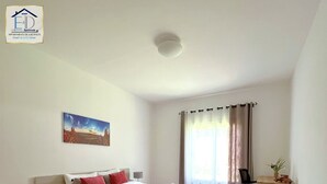 A modern bedroom with a bed, bedside tables, a desk, and a window with curtains. - E&D  Apartment With Private Garden, Quiet and Secure Ideal For Families (Antananarivo)