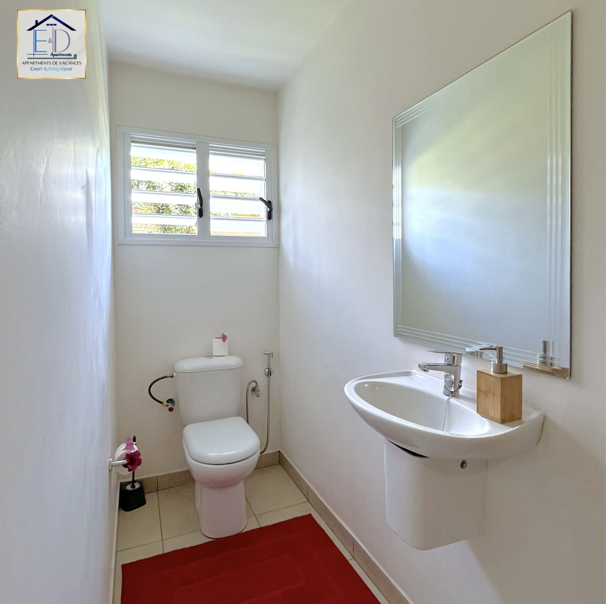 A small, white bathroom with a toilet, sink, and window.