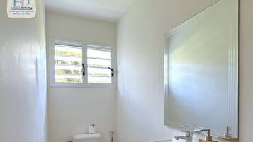 A small, white bathroom with a toilet, sink, and window.