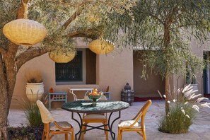 A round table with wicker chairs, a potted plant, and a hanging basket. - Agafay Desert Hotel (Agafay)