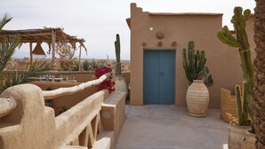 A rooftop terrace with a blue door, cacti, and a pergola with flowers. - Agafay Desert Hotel (Agafay)