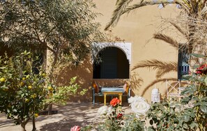 A courtyard with a bench, a table, and a decorative lantern. - Agafay Desert Hotel (Agafay)