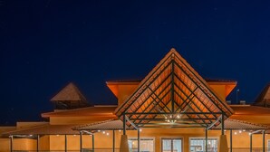 Un hotel con una llamativa estructura de techo triangular, una entrada cubierta y una fachada bien iluminada.