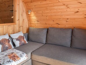 A wooden-paneled room with a grey sofa, two pillows with animal prints, and a wall-mounted light fixture. - 1 bedroom accommodation in Corney, near Millom (Corney, near Millom)