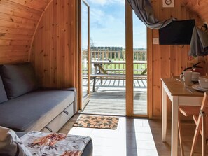 A wooden cabin with a sofa, a dining table, and a view of a deck and outdoor area. - 1 bedroom accommodation in Corney, near Millom (Corney, near Millom)