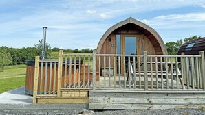 A wooden cabin with a large arched entrance, a wooden deck, and a chimney. - 1 bedroom accommodation in Corney, near Millom (Corney, near Millom)