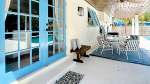 A covered outdoor area with a pool, blue-framed windows, a ceiling fan, and outdoor furniture. - Mermaids' BeachHouse: Walk2Beach • Pool • KingBed (Cocoa Beach)