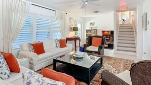 A living room with a white sofa, a black coffee table, and a patterned rug. - Mermaids' BeachHouse: Walk2Beach • Pool • KingBed (Cocoa Beach)