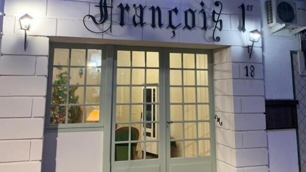 A hotel named "Hotel Francoise 1" with a light-colored facade, a green door, and a small porch area.