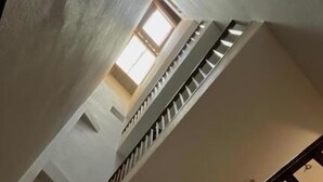 A multi-level interior with a staircase, a framed picture on the wall, and a window allowing natural light.