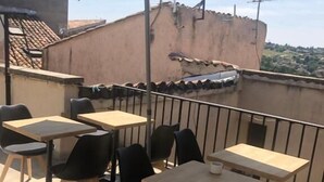 A rooftop terrace with outdoor seating, including tables and chairs, and a large umbrella providing shade.