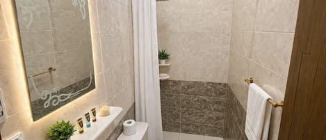 A modern bathroom with a shower, toilet, sink, and a large mirror.