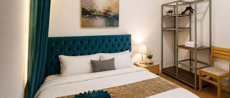 Une chambre d’hôtel comprenant un lit, une table de chevet, une lampe, un tableau, une armoire et une chaise.