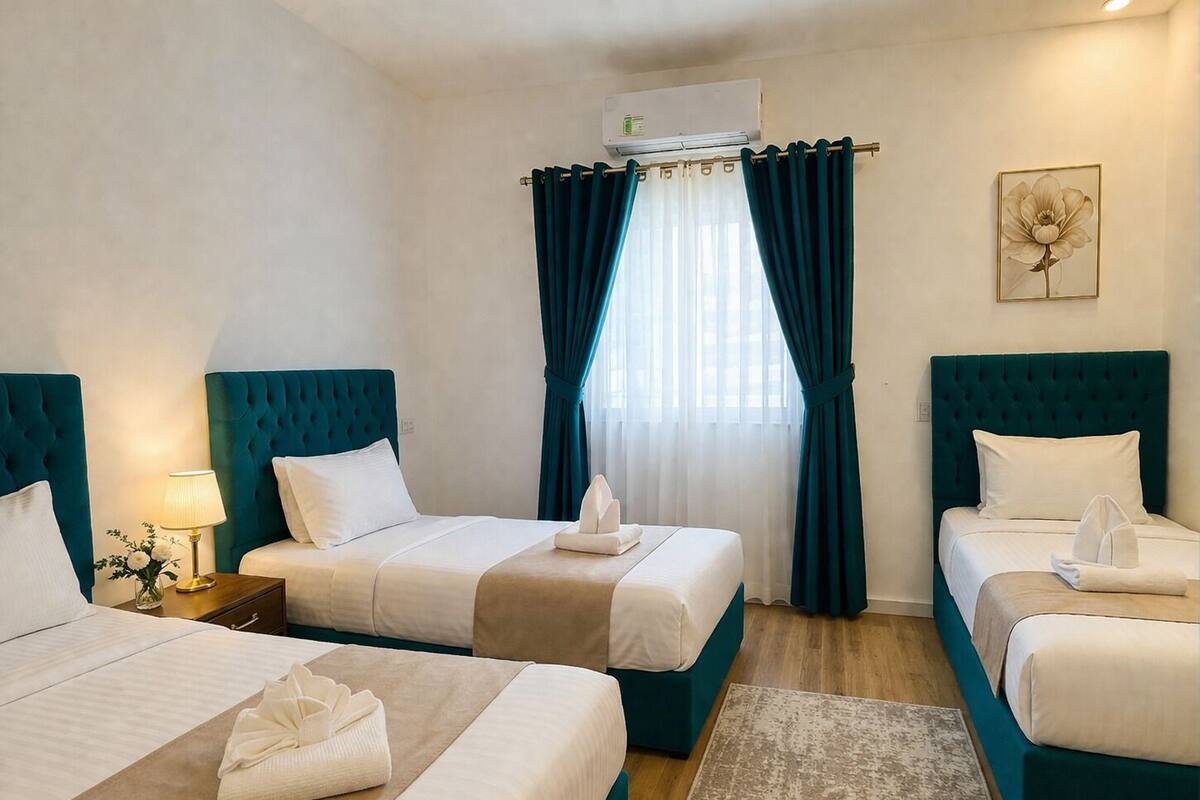 A hotel room with two beds, a large window with curtains, an air conditioning unit, and a framed picture on the wall.