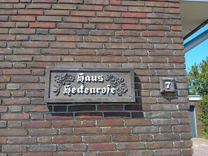 A brick wall with a sign that reads 'Haus Hedenroth' and a number '7' indicating the address. - Heckenrose7- Souterrain Rechts (Norddorf auf Amrum)