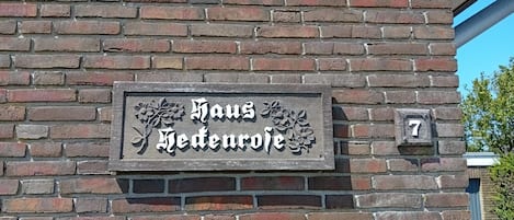 A brick wall with a sign that reads 'Haus Hedenroth' and a number '7' indicating the address.