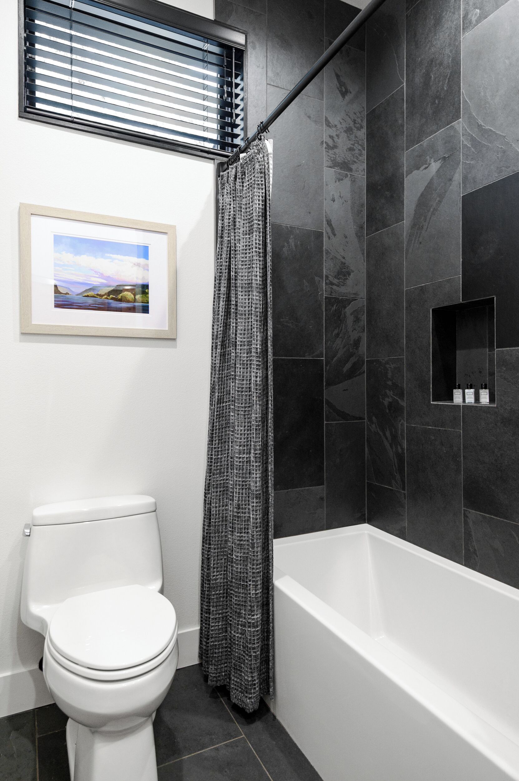 A bathroom with a white toilet, a shower curtain, and a bathtub.