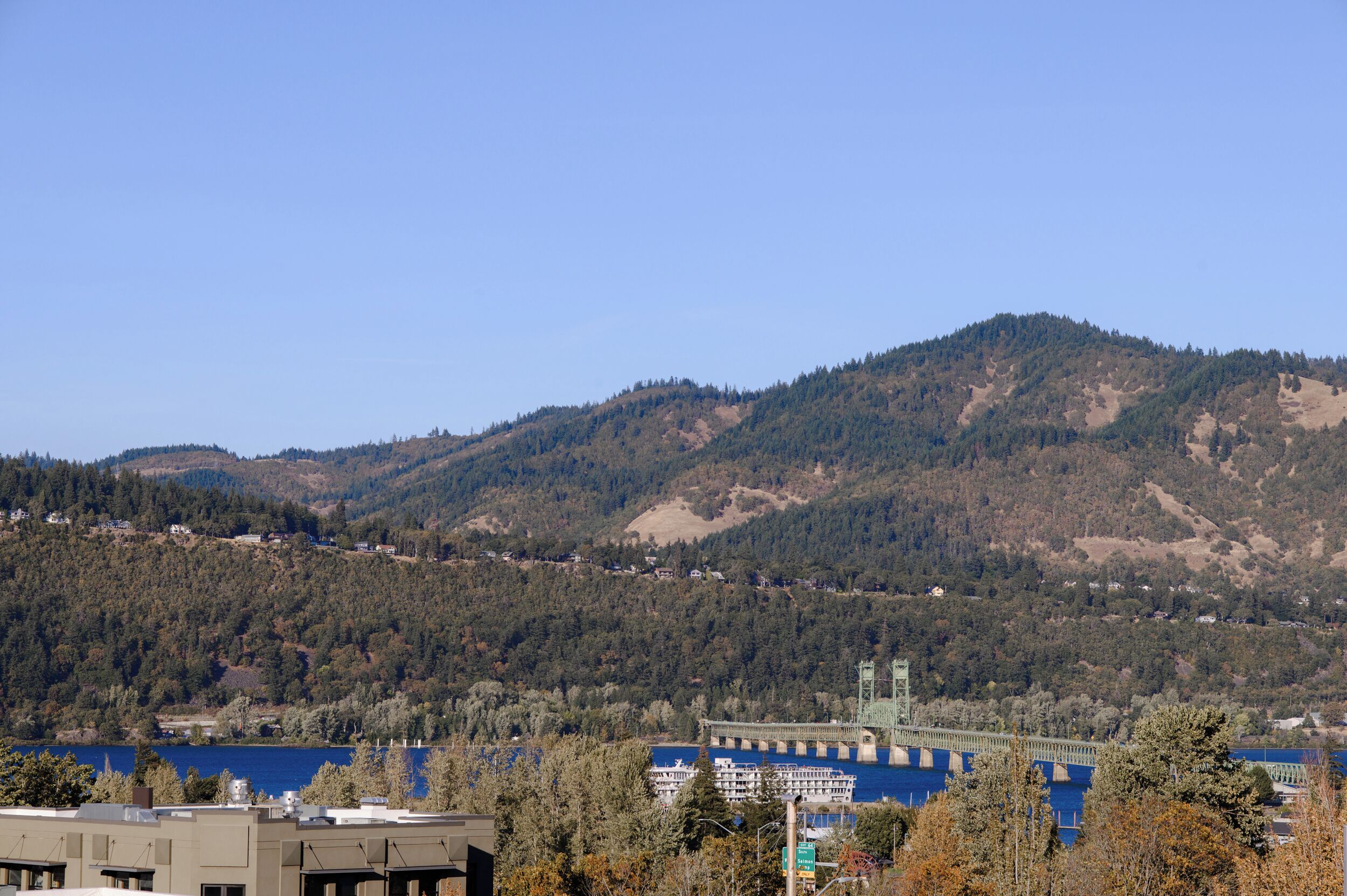 A view of a mountainous landscape with a bridge over a body of water, surrounded by trees and buildings.