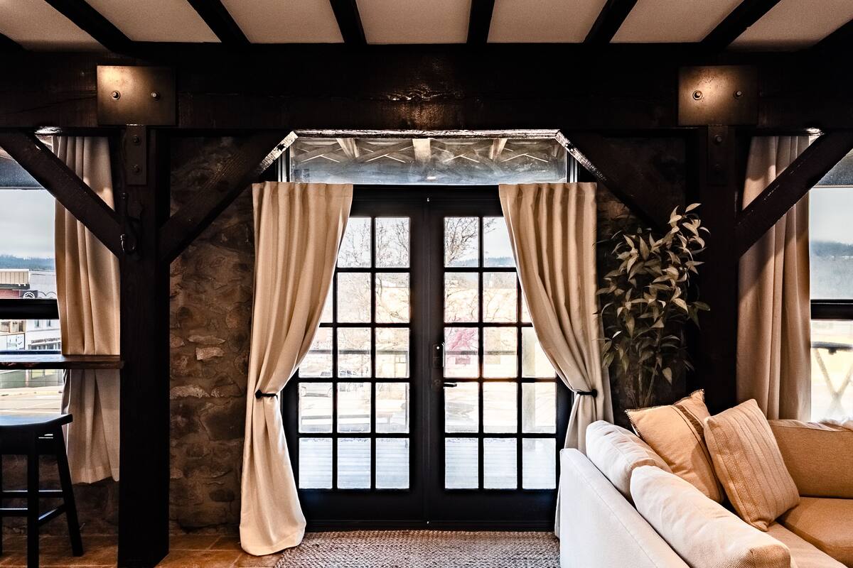 A cozy room with a large window, a sofa, and a potted plant.