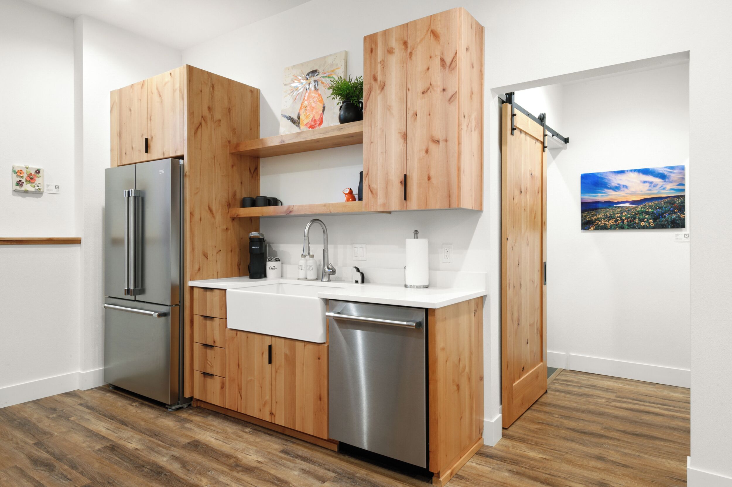 A modern kitchen with wooden cabinets, stainless steel appliances, and a white countertop.