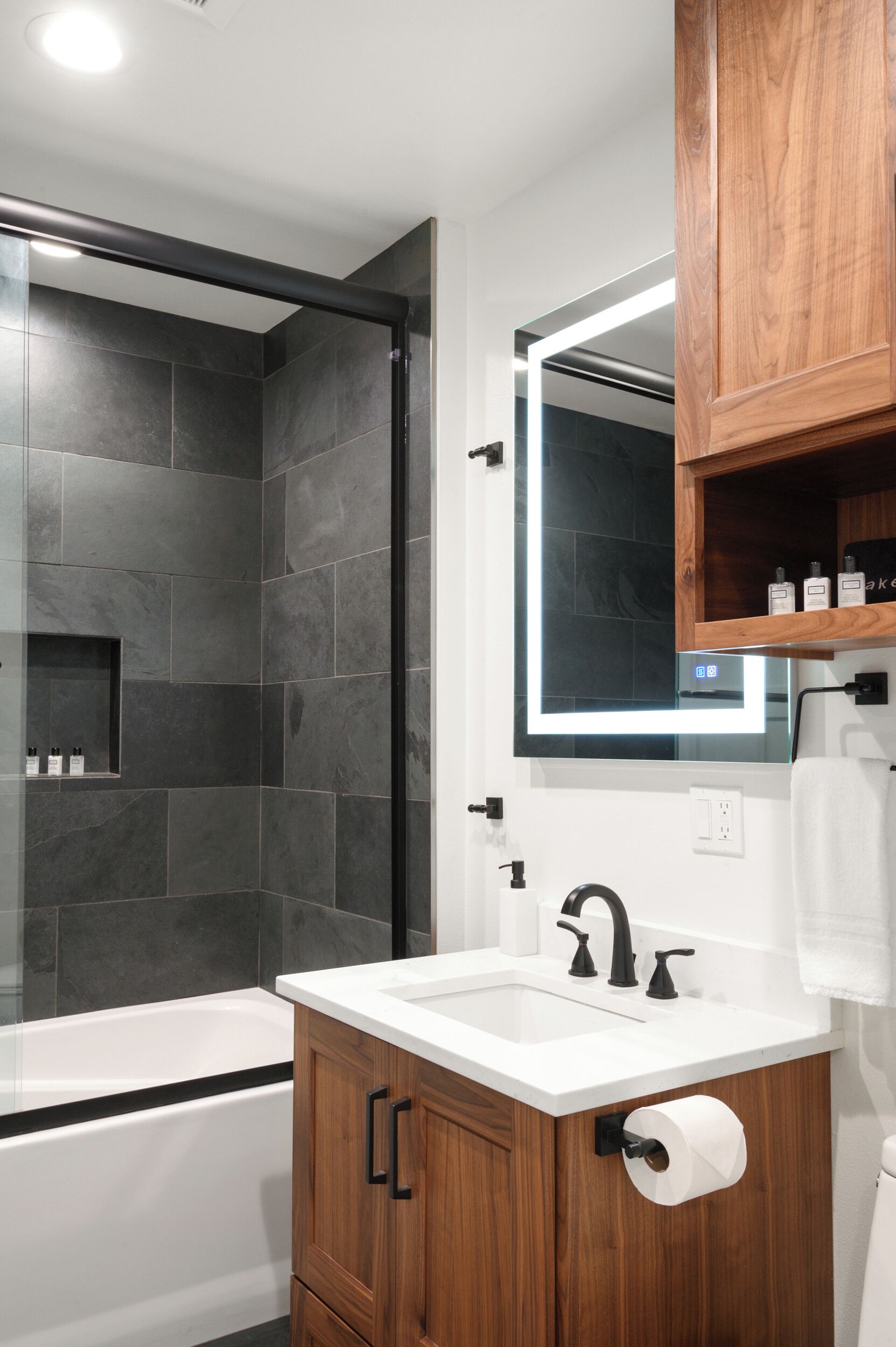 Un baño moderno con ducha, bañera, lavabo y armarios de madera.