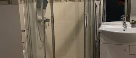 A modern bathroom with a glass-enclosed shower, a wooden toilet, and a white sink with a mirror above it.