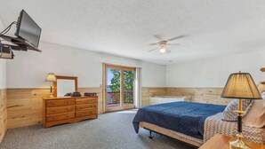 A bedroom with a bed, a dresser, a TV mounted on the wall, a ceiling fan, and a balcony door. - Lakeside Condo #19 4BR 4BA Timberlane Resort (Park Rapids)
