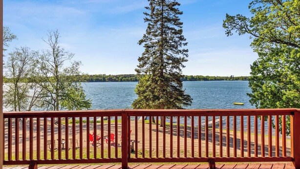 A wooden deck with a railing overlooking a lake, surrounded by trees. - Lakeside Condo #19 4BR 4BA Timberlane Resort (Park Rapids)