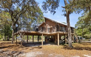 A wooden cabin with a deck, surrounded by trees. - Nature at it`s best with the room to explore it (Cedar Key)