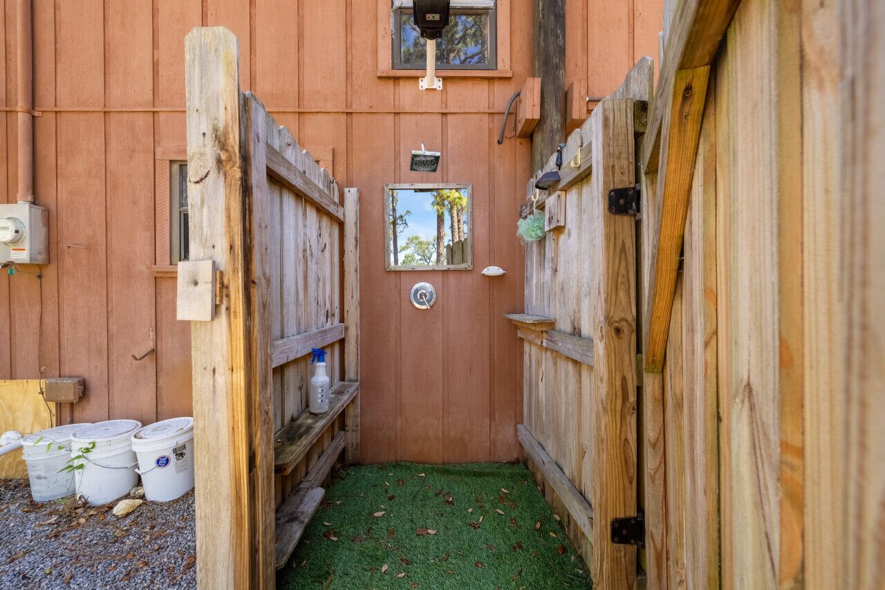 A narrow wooden corridor with a green artificial turf floor, leading to a door with a small window.