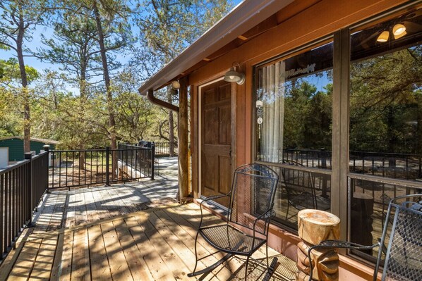 A wooden deck with a glass door leading to a covered area, surrounded by trees. - Nature at it`s best with the room to explore it (Cedar Key)