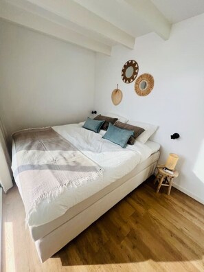 Un dormitorio con cama, suelo de madera y adornos en la pared.