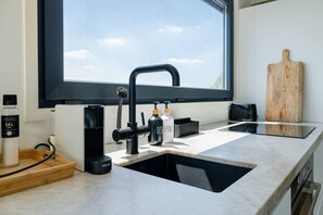 Una cocina moderna con un grifo negro, una cafetera y una tabla de cortar de madera sobre la encimera.