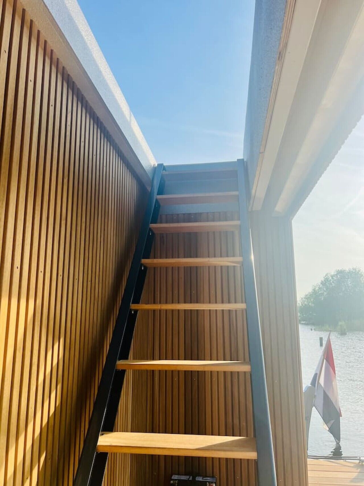 Un escalier en bois mène à une terrasse offrant une vue sur une étendue d’eau.