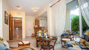 Una sala de estar con una mesa de comedor, sillas y un sofá. Se ve una escalera que lleva a otra habitación.