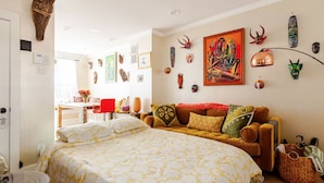 Une chambre confortable avec un grand lit, un canapé et un coin repas agrémenté d’une chaise rouge.