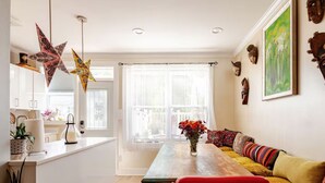 Un salon moderne avec une table à manger en bois, des coussins colorés et un vase rempli de fleurs.