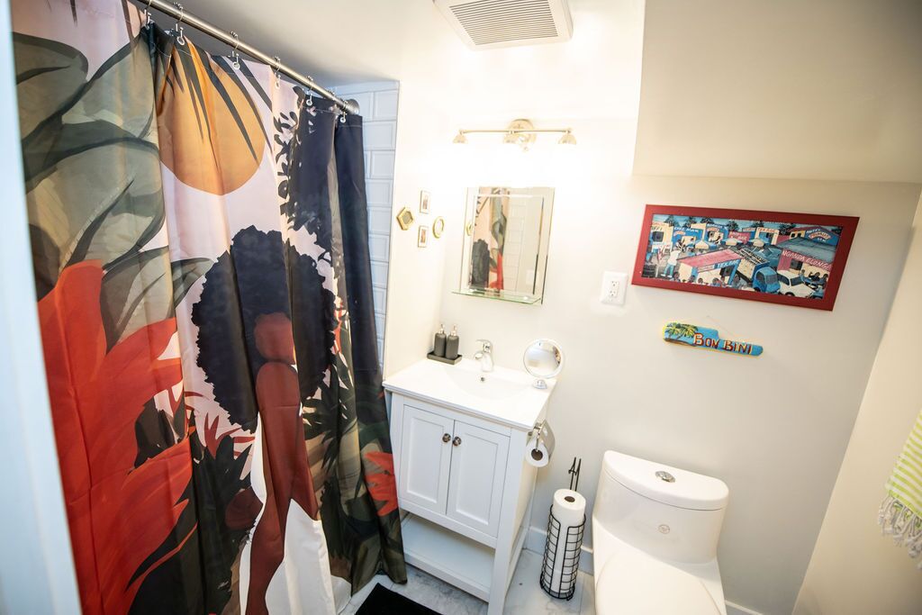 Ein Badezimmer mit Duschvorhang, Waschbecken, Toilette und Spiegel.