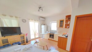 A bedroom with a bed, a TV, a desk, and a kitchenette. - Sea View Apartment Luka (Novalja)