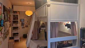 Ein Schlafzimmer mit Etagenbett, Kleiderschrank, einer Pendelleuchte und einer Wand mit verschiedenen Dekorationen.