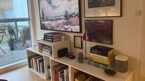 Ein Wohnzimmer mit einem großen Flachbildfernseher an der Wand, umgeben von Bücherregalen voller Bücher und Dekoration.