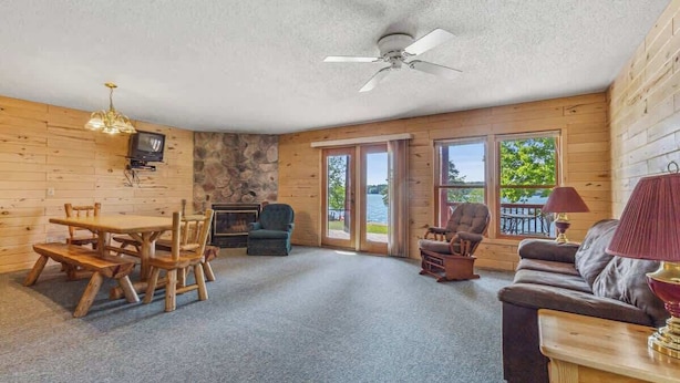 L'intérieur d'une cabane comprenant une table à manger, des chaises, un canapé, une cheminée et une vue sur l'extérieur.