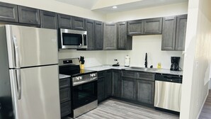 A modern kitchen with stainless steel appliances, dark wooden cabinets, and a light-colored countertop. - Loft near Bennett Springs State Park (Lebanon)