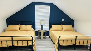 A bedroom with two beds, a small table, and a window with blinds. - Loft near Bennett Springs State Park (Lebanon)