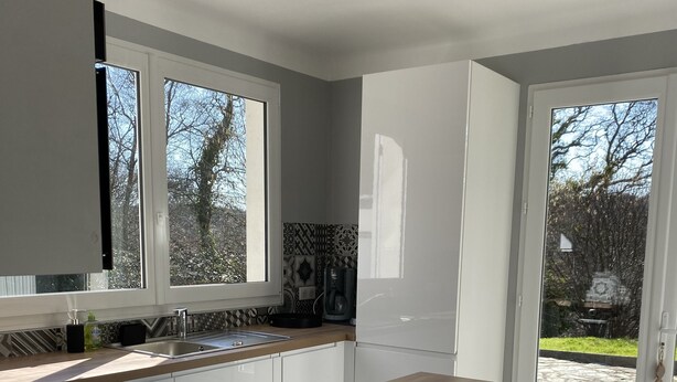 Una cocina moderna con encimera de madera, armarios blancos y un ventanal grande.