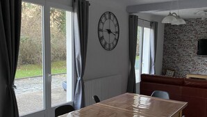 Un comedor con una mesa y sillas de madera, un reloj de pared y una pared de ladrillo.