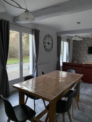 Enjoy meals in this dining area with a large table and comfortable seating for four, surrounded by a sliding glass door leading to an outdoor space.